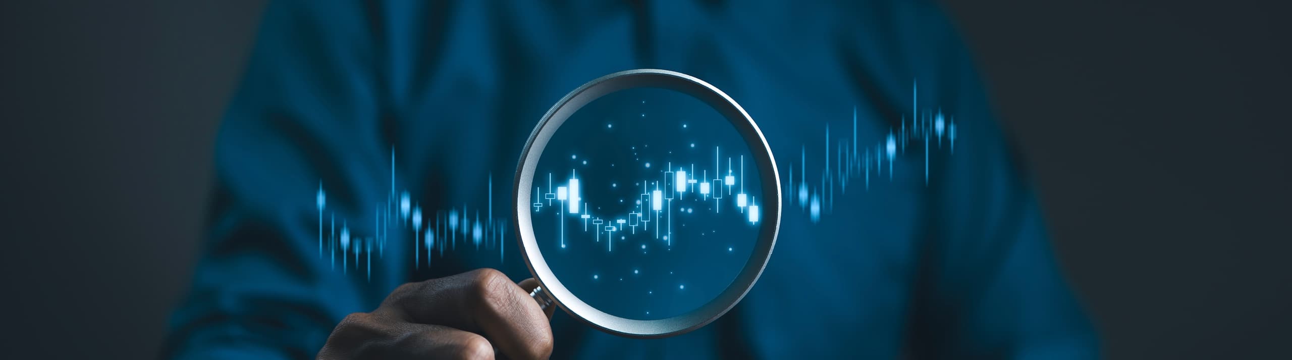 A close-up of a hand holding a magnifying glass that focuses on glowing blue audio soundwaves and digital data.