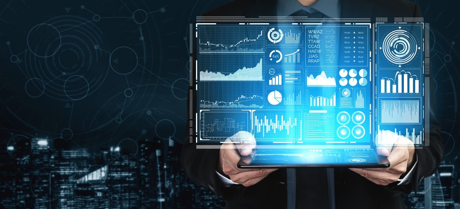 A person in a suit holding a tablet projecting a bright blue digital dashboard with graphs, charts, and metrics over a city skyline.