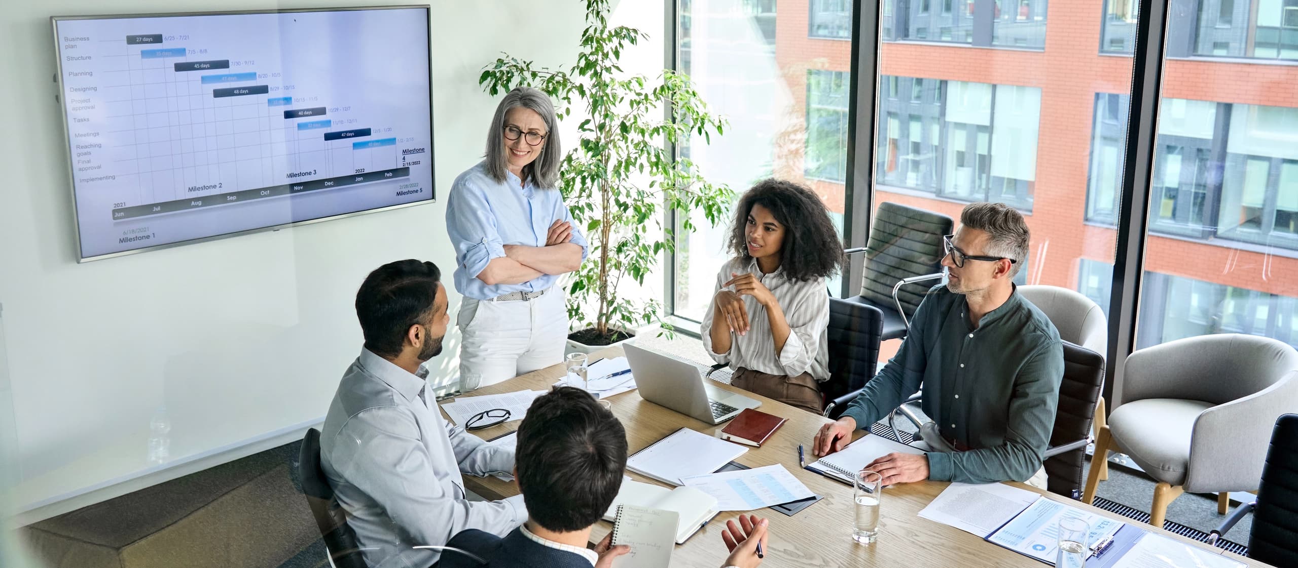 Elevated view of a diverse group of colleagues in a boardroom having a meeting and smiling.