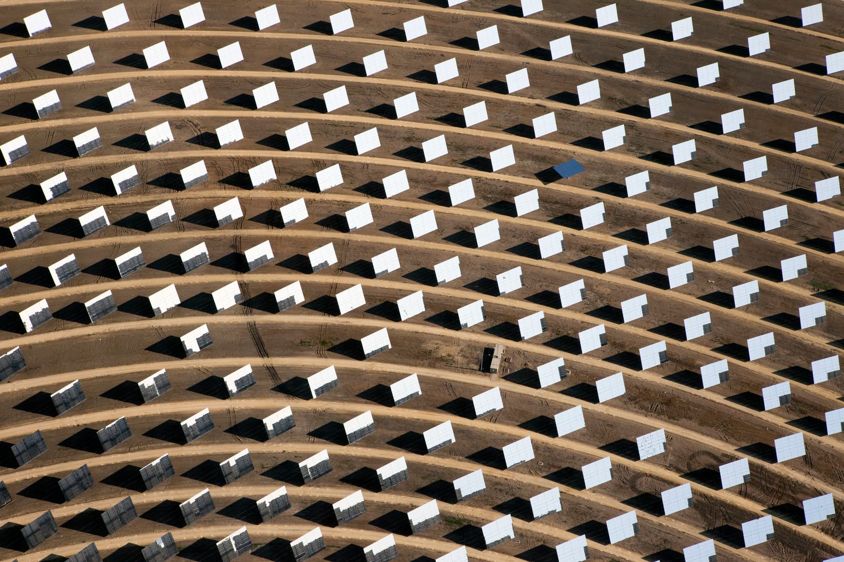 Abstract aerial image of solar panels in field forming a pattern.