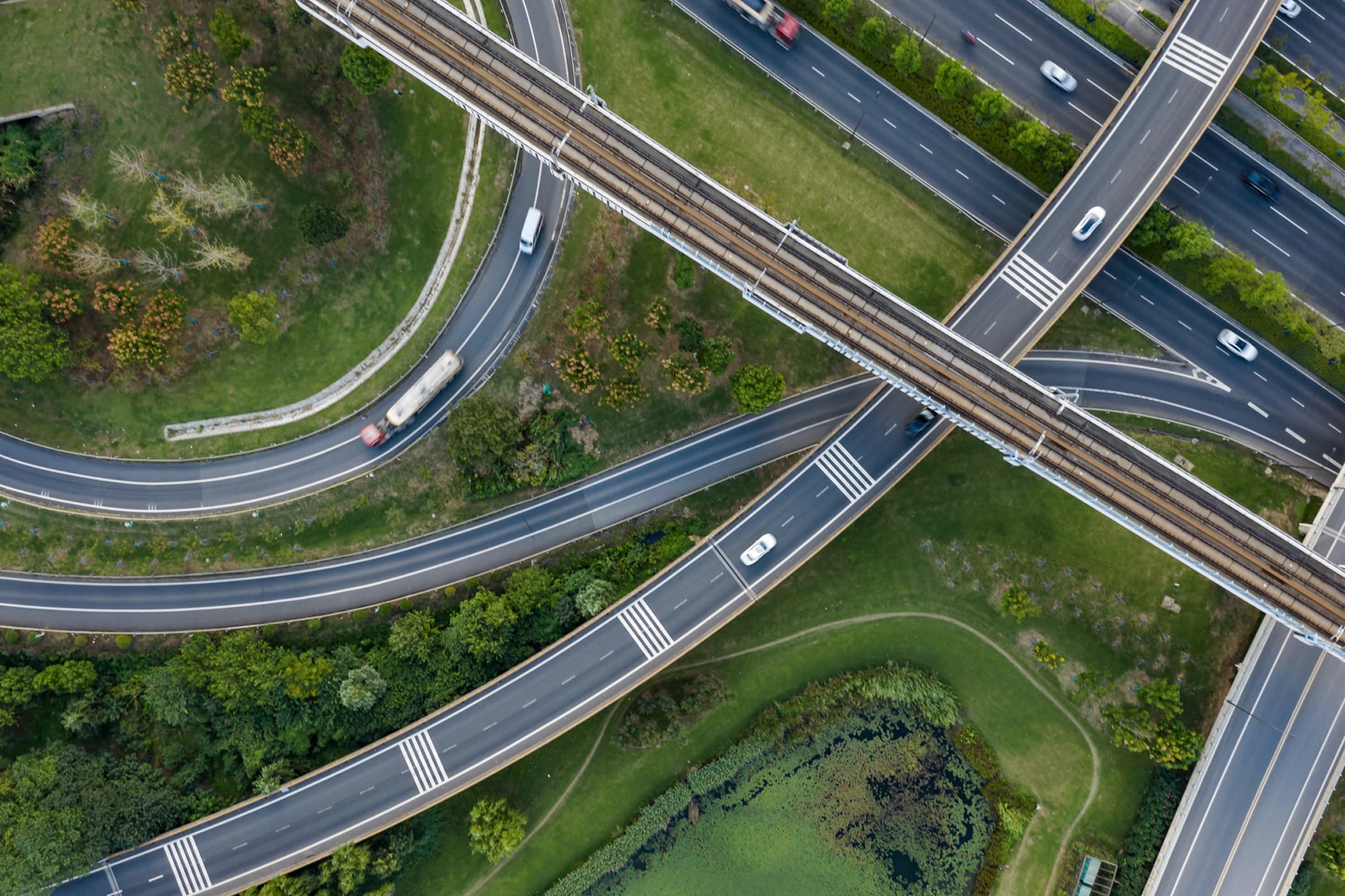 Aerial view of a curved highway and railway interchange surrounded by green fields.