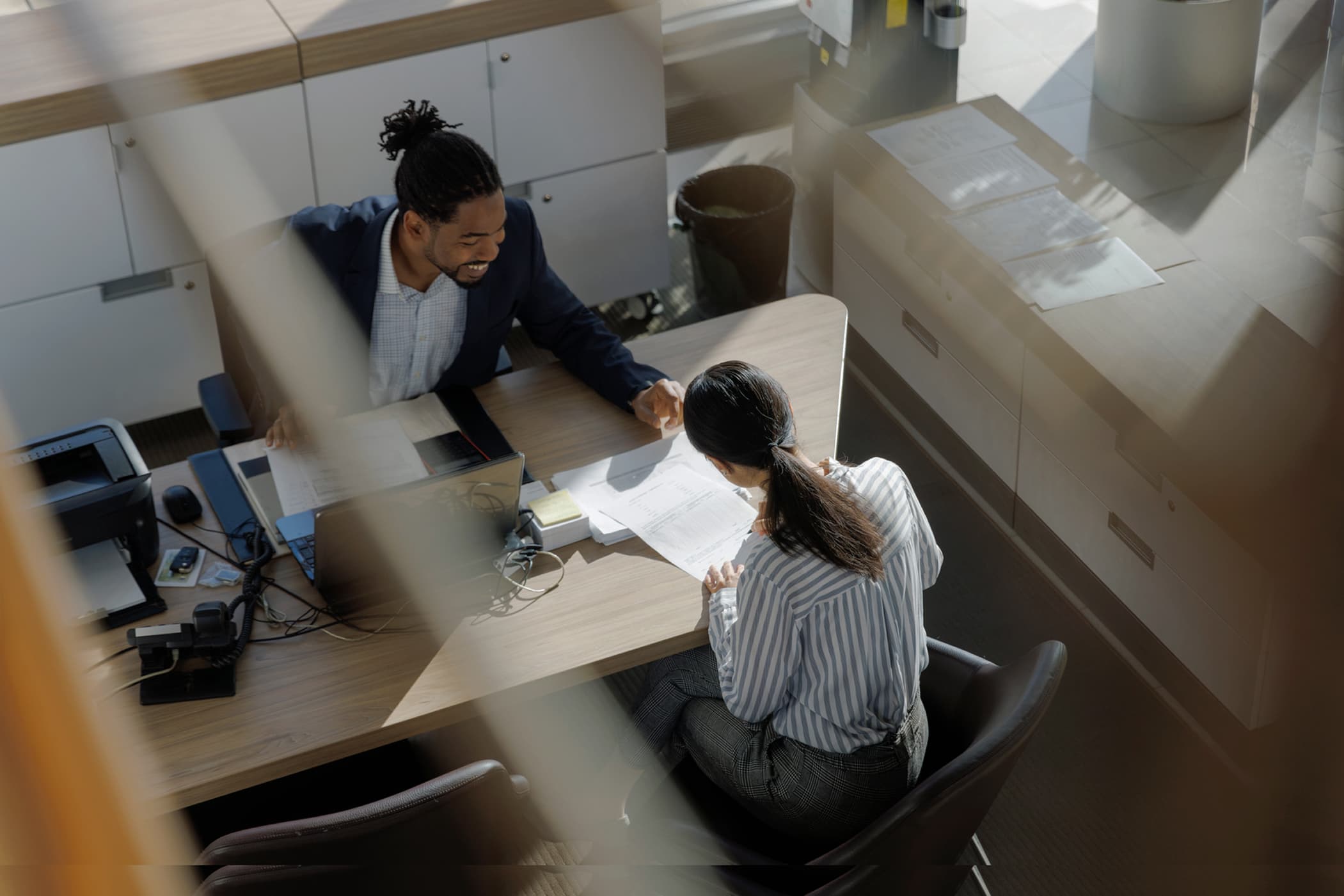 Top view of a consultant and a client discussing business at a desk.