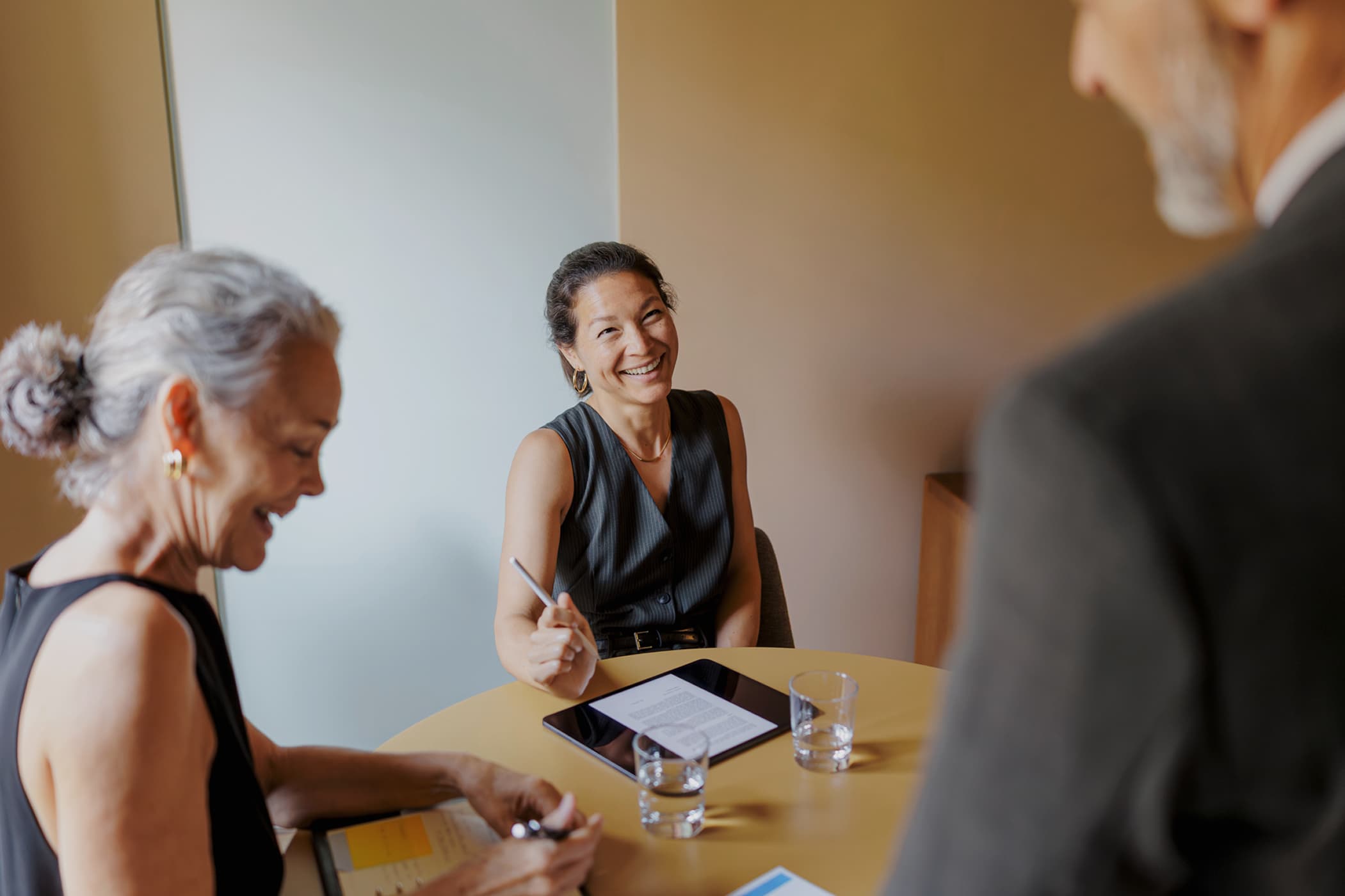 A smiling businesswoman in a meeting with colleagues.