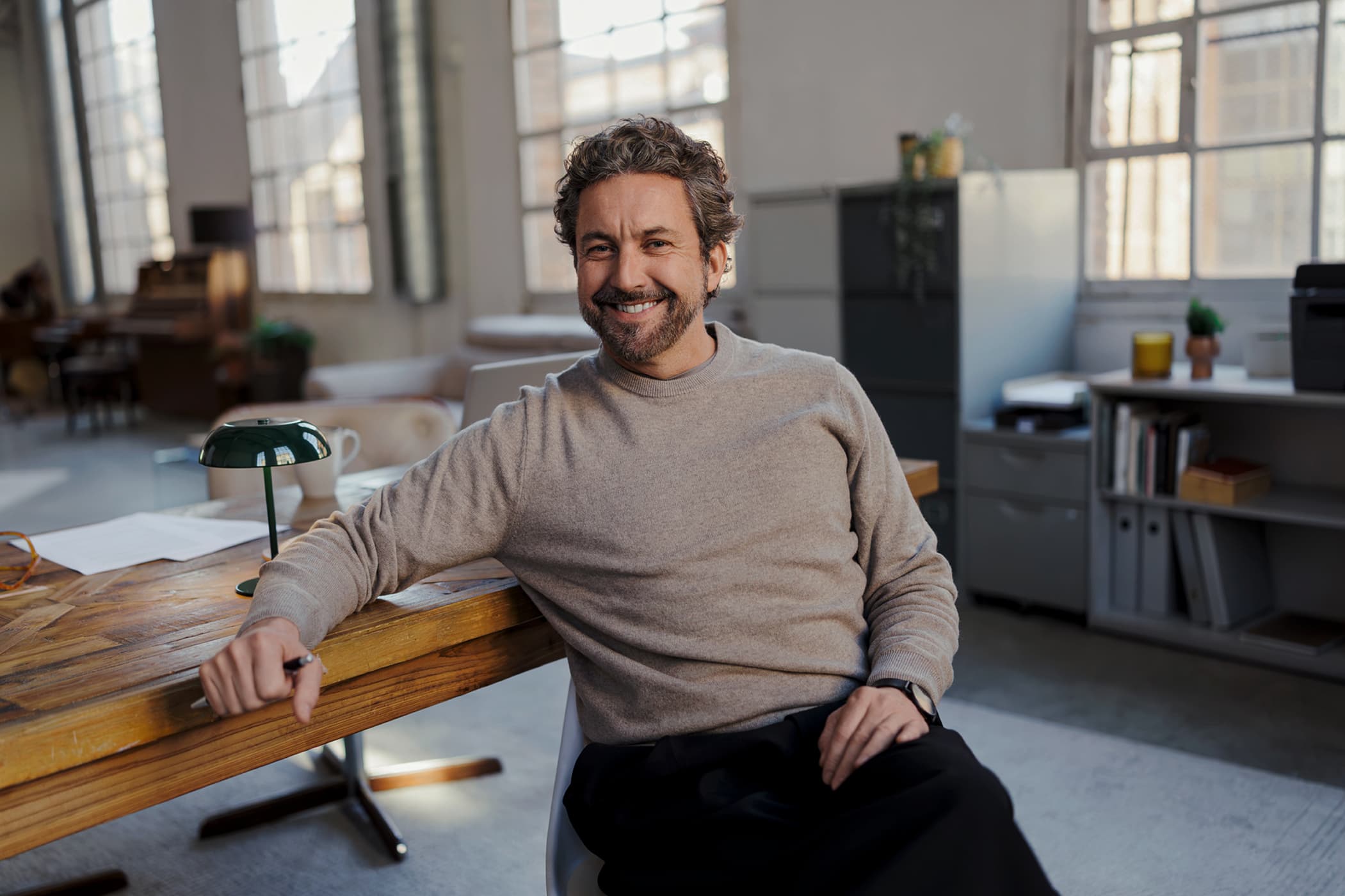 Smiling man sitting at his desk in a bright office.