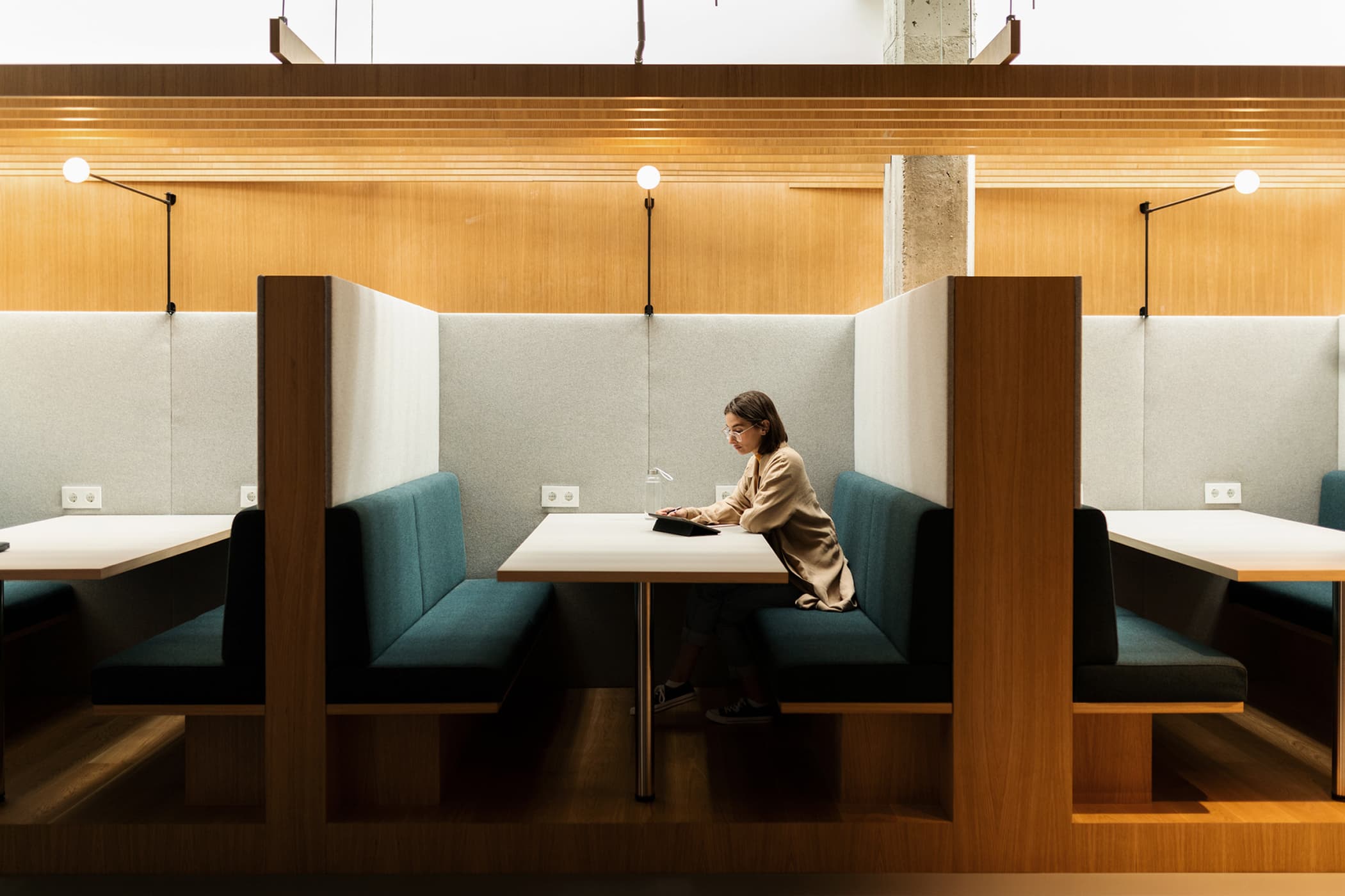 A woman working on a digital tablet in a modern office booth.