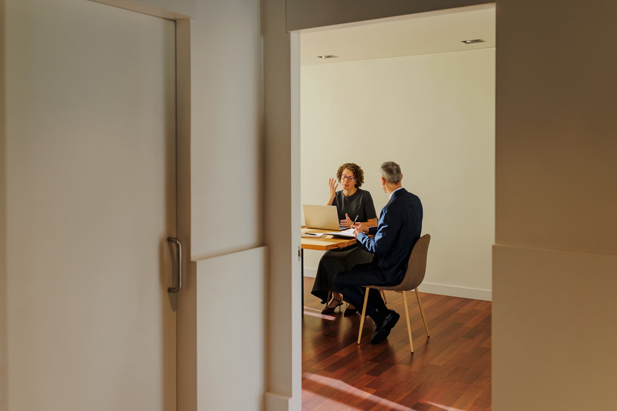 Outside view of a doorway into a meeting room where two individuals are having a meeting.